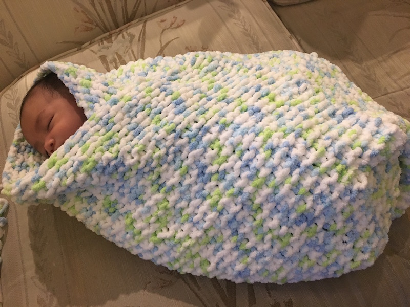 baby wrapped in knit garter stitch blanket