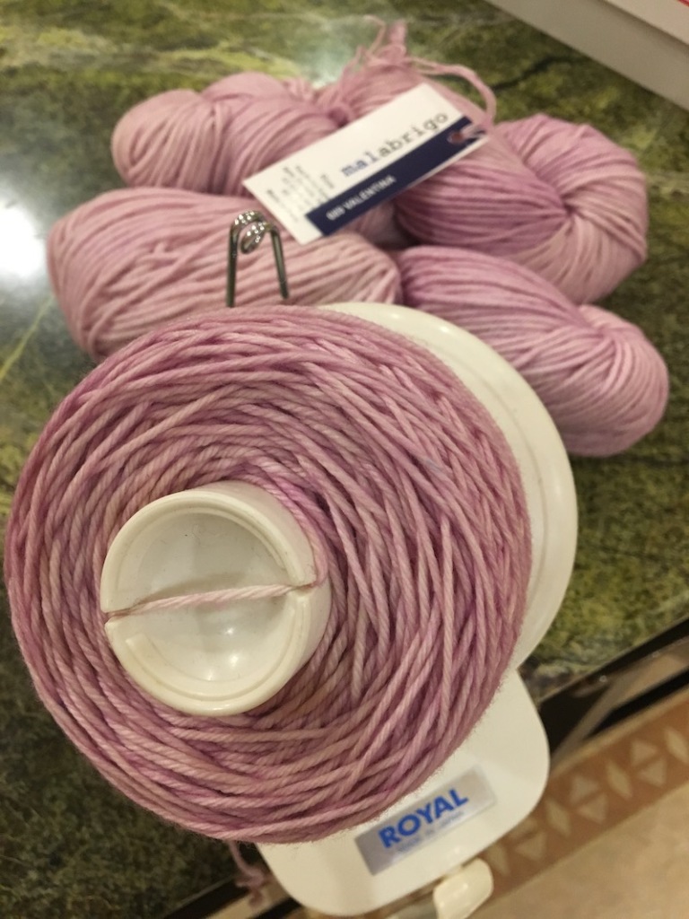 pink yarn on ball winder with two skeins in background